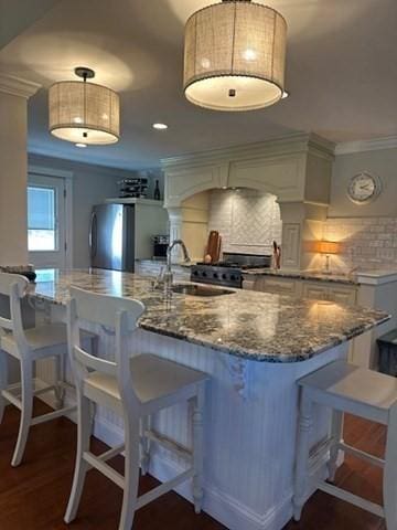 kitchen with decorative backsplash, dark wood-style floors, freestanding refrigerator, crown molding, and a sink