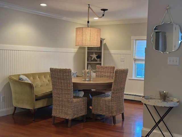 dining room with crown molding, a baseboard heating unit, wood finished floors, and wainscoting