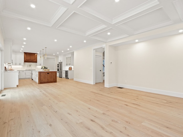 unfurnished living room with sink, coffered ceiling, beamed ceiling, crown molding, and light wood-type flooring