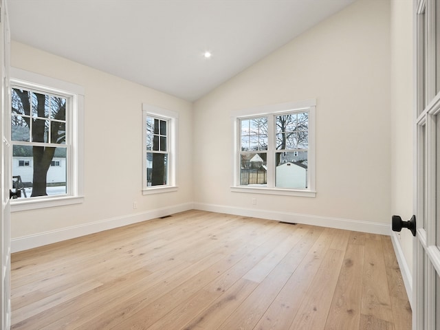 spare room with light hardwood / wood-style flooring and lofted ceiling