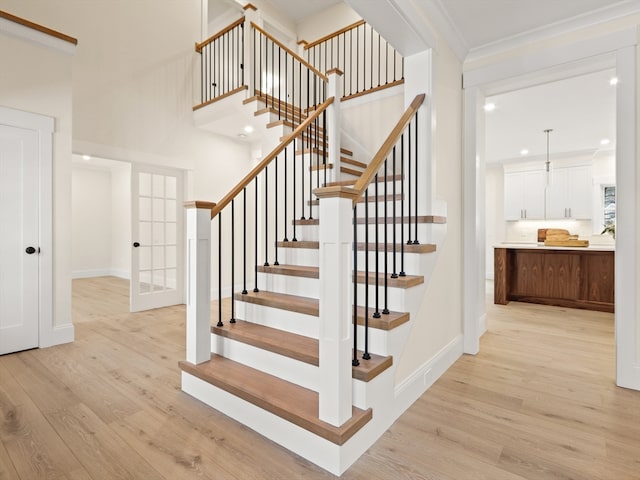 staircase featuring wood-type flooring and ornamental molding