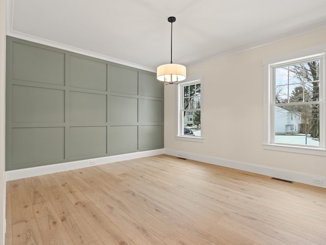 unfurnished dining area featuring a healthy amount of sunlight, light hardwood / wood-style floors, and ornamental molding