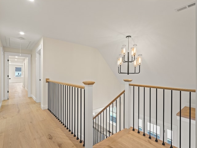 corridor with light hardwood / wood-style flooring and a chandelier