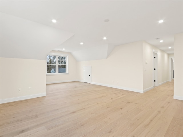 bonus room with light wood-type flooring and vaulted ceiling