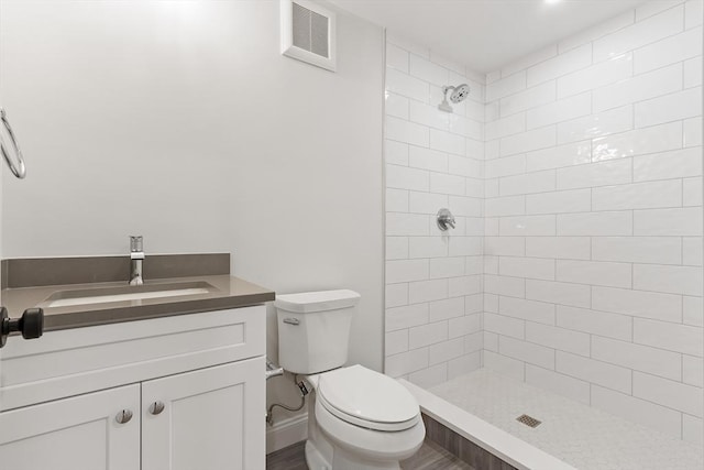 bathroom with tiled shower, vanity, and toilet