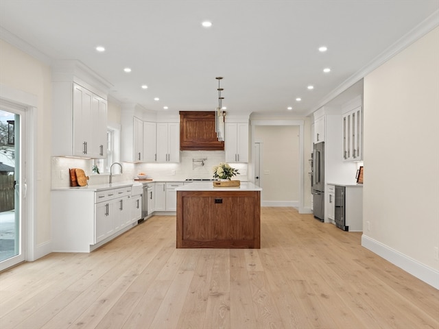 kitchen with a kitchen island, light hardwood / wood-style floors, ornamental molding, and white cabinetry