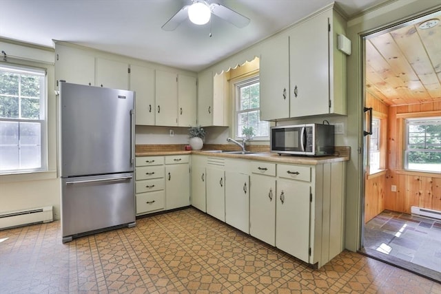 589 Turnpike, Ashby, MA 01431 - kitchen with appliances with stainless steel finishes, baseboard heating, healthy amount of natural light, ceiling fan, and wooden walls