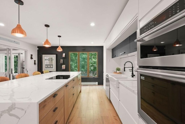 kitchen featuring appliances with stainless steel finishes, a baseboard radiator, a spacious island, healthy amount of natural light, and recessed lighting