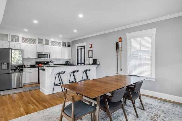 dining room with light wood finished floors, baseboards, ornamental molding, and recessed lighting