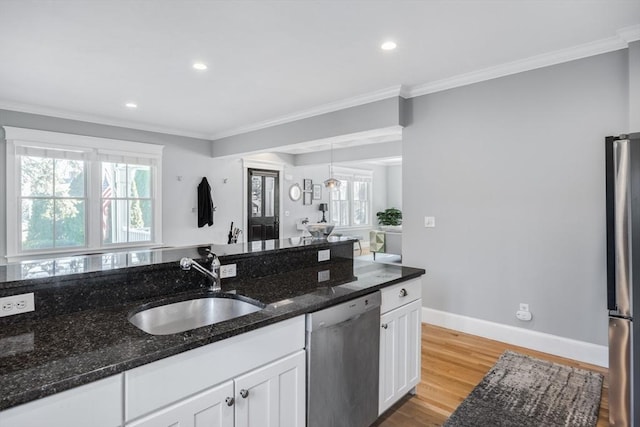 kitchen with a sink, stainless steel appliances, white cabinets, plenty of natural light, and light wood-style floors