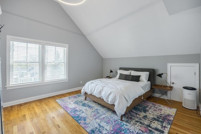 bedroom with baseboards, wood finished floors, and lofted ceiling
