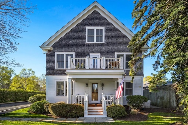 view of front of property with covered porch, fence, and a balcony