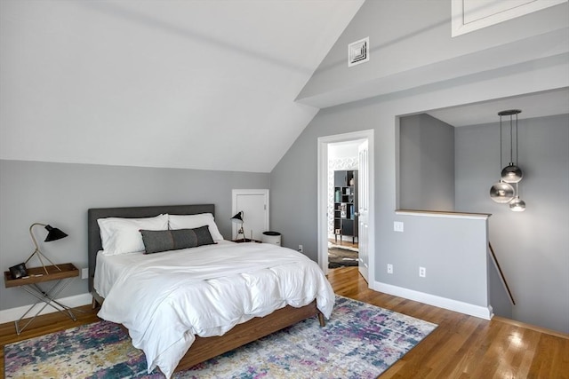 bedroom with baseboards, wood finished floors, and vaulted ceiling