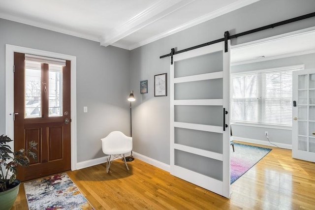 foyer with a barn door, plenty of natural light, wood finished floors, and ornamental molding