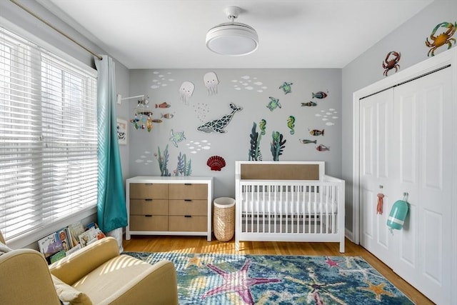bedroom featuring a closet, a crib, and wood finished floors