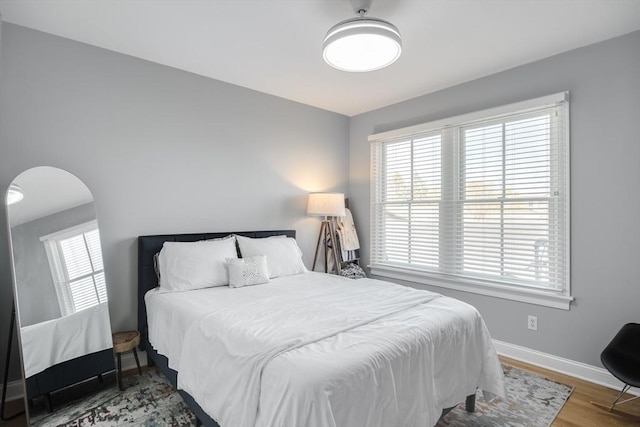 bedroom featuring wood finished floors, baseboards, and arched walkways