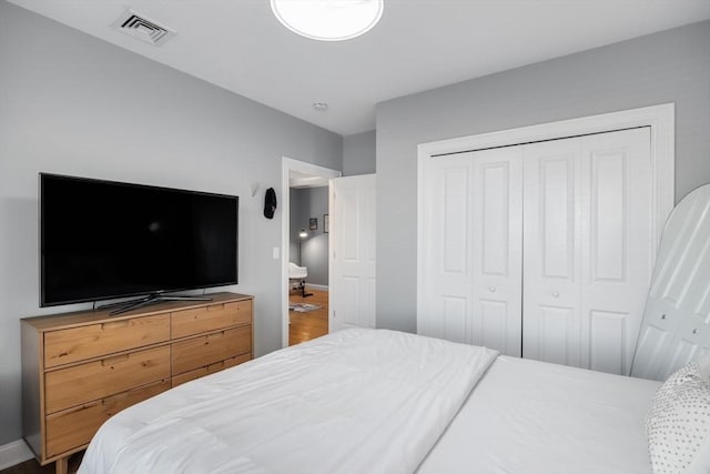 bedroom with baseboards, a closet, visible vents, and wood finished floors