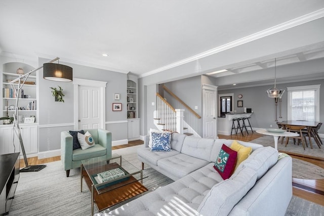 living room with stairway, wood finished floors, baseboards, and built in shelves