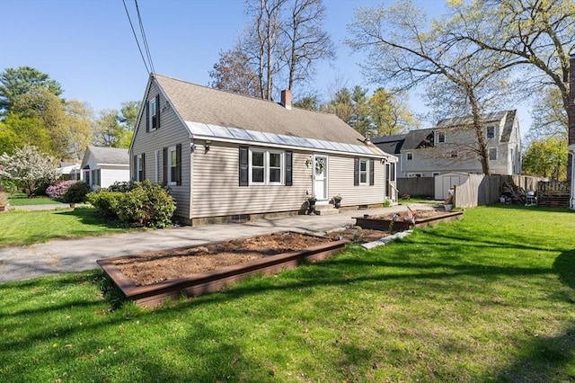 view of front of house featuring fence, a chimney, a shed, and a front yard