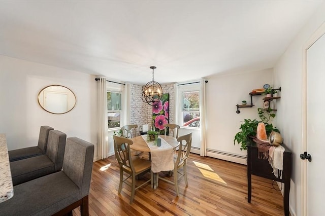 dining space with a notable chandelier, a healthy amount of sunlight, baseboard heating, and light wood-style floors