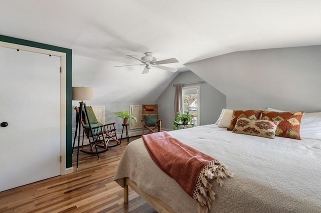 bedroom with ceiling fan, vaulted ceiling, and wood finished floors
