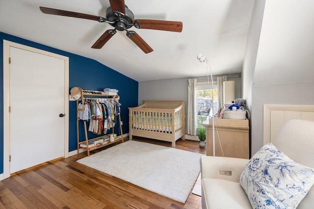 bedroom with a ceiling fan, baseboards, wood finished floors, lofted ceiling, and a closet