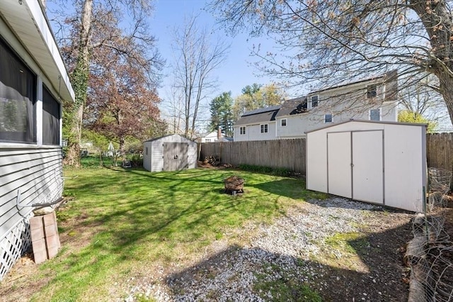 view of yard featuring a storage unit, a fenced backyard, a fire pit, and an outdoor structure