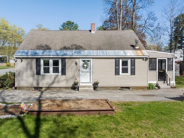 back of house featuring a lawn, roof with shingles, a chimney, and entry steps