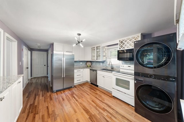 kitchen featuring a sink, white cabinets, stacked washer and clothes dryer, and stainless steel appliances