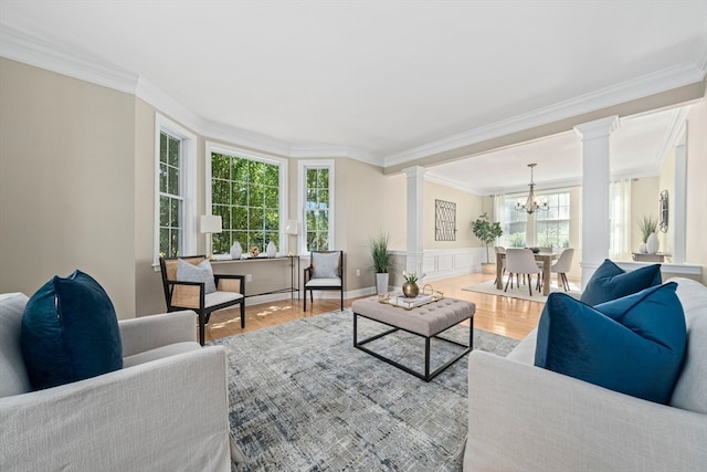 living room with hardwood / wood-style flooring, decorative columns, crown molding, and a notable chandelier