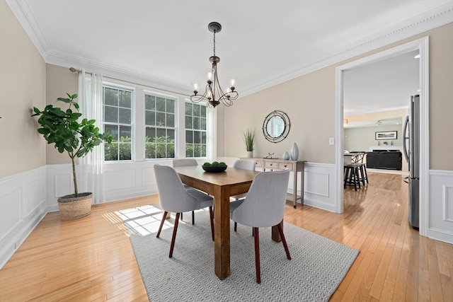 dining room with light wood-type flooring, an inviting chandelier, and ornamental molding