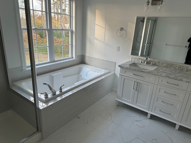 bathroom with vanity and tiled tub