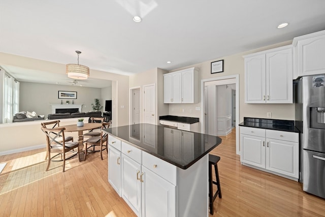 kitchen with white cabinetry, a center island, hanging light fixtures, stainless steel fridge with ice dispenser, and light hardwood / wood-style floors