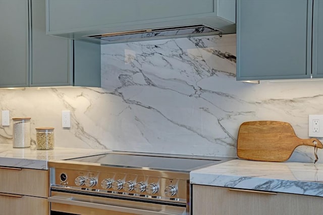 details featuring light stone countertops, under cabinet range hood, stainless steel electric stove, and decorative backsplash