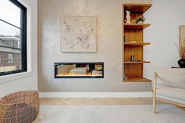 sitting room with a glass covered fireplace and baseboards