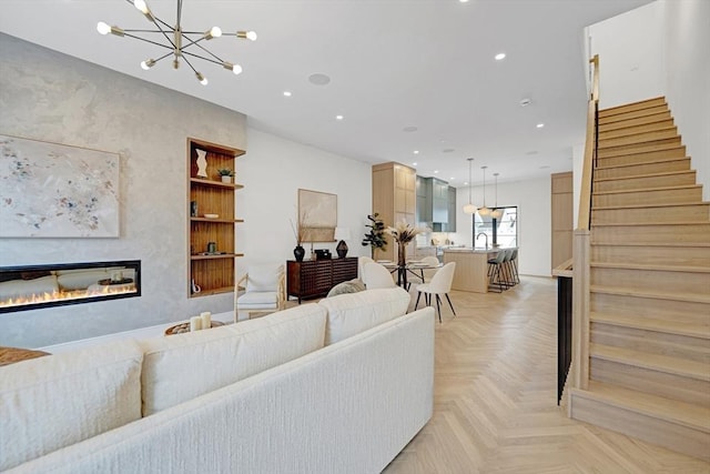 living room with an inviting chandelier, recessed lighting, stairway, and a glass covered fireplace