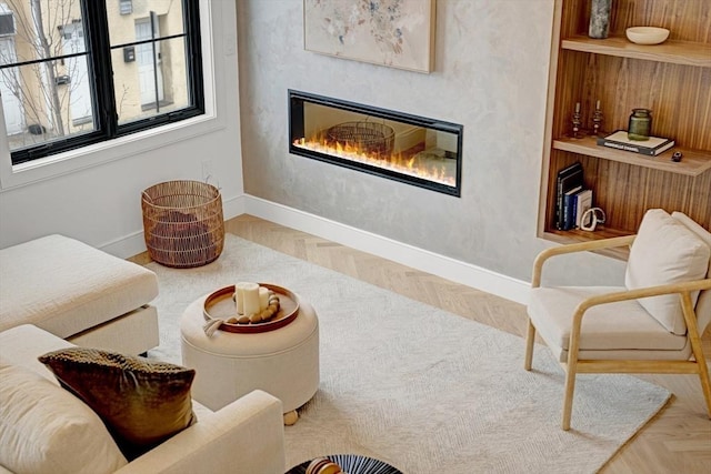 living area featuring a glass covered fireplace and baseboards