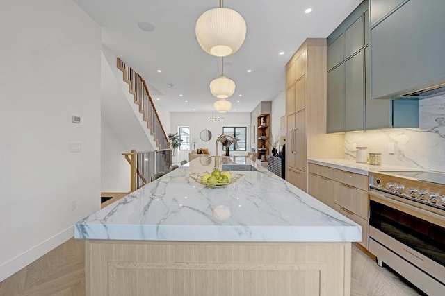 kitchen featuring light stone counters, stainless steel electric range oven, a large island, backsplash, and light brown cabinetry