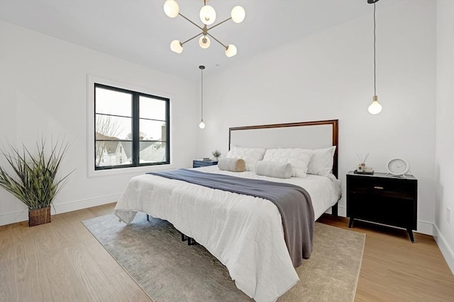 bedroom featuring light wood-type flooring, a notable chandelier, and baseboards