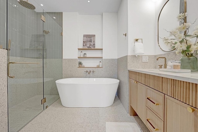 full bathroom featuring a freestanding tub, vanity, tile walls, wainscoting, and a shower stall