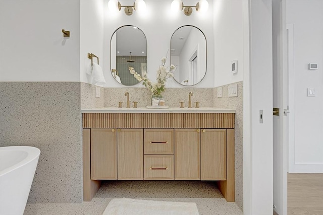 full bath with a soaking tub, wainscoting, a sink, and double vanity