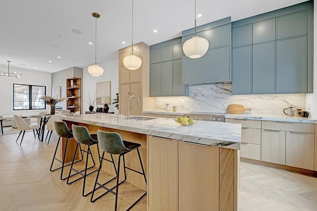 kitchen featuring light stone counters, a sink, backsplash, and modern cabinets