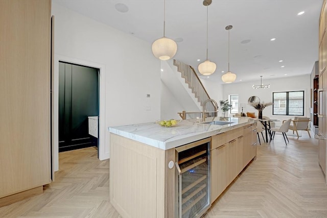 kitchen with light stone counters, beverage cooler, a spacious island, a sink, and light brown cabinetry