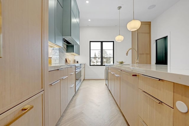 kitchen featuring stainless steel range, modern cabinets, light stone countertops, light brown cabinetry, and a sink