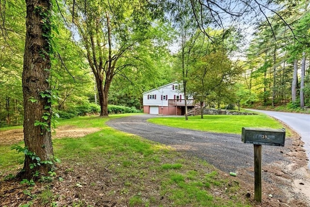 39 Mashapaug Rd, Sturbridge, MA 01566 - view of front of house featuring an attached garage, a front yard, a wooden deck, driveway, and a wooded view