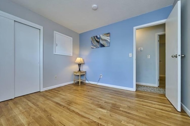 unfurnished bedroom featuring light wood-type flooring, baseboards, and a closet