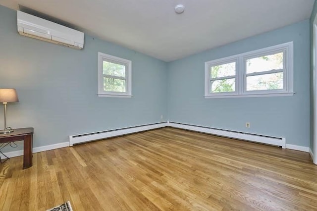 spare room featuring a wall unit AC, wood finished floors, a baseboard heating unit, and baseboards