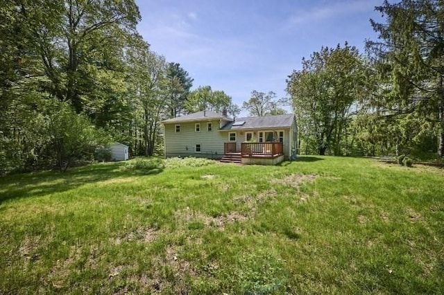 rear view of house featuring a wooden deck, an outbuilding, a yard, and a storage unit