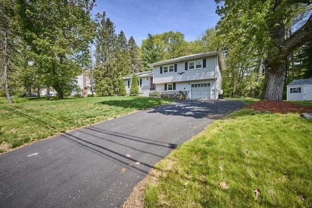 tri-level home with asphalt driveway, a front yard, and an attached garage