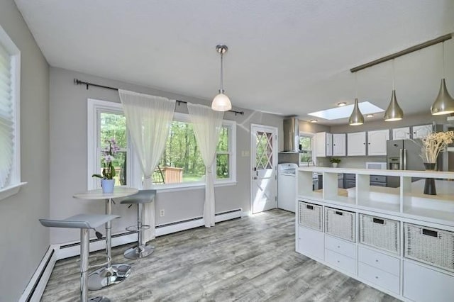 kitchen featuring exhaust hood, light wood-style floors, light countertops, and decorative light fixtures